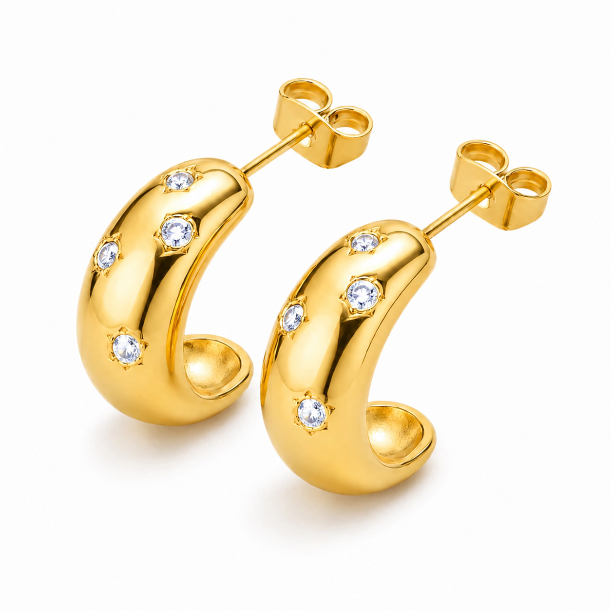 A pair of gold crescent-shaped hoop earrings with small clear gemstones set along the front, displayed on a clean white background.
