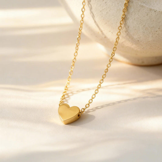 A delicate gold chain necklace with a small, polished gold heart pendant